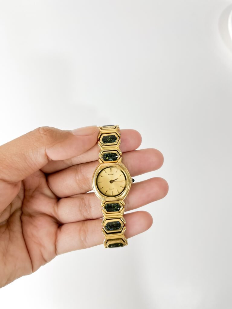 A hand holding a gold-tone vintage watch